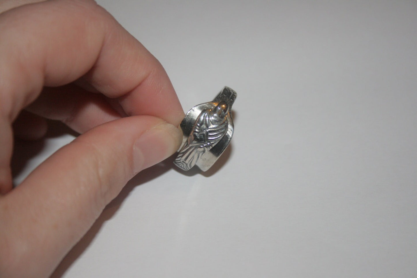 Upcycled silver ring made from antique apostle spoon with detailed apostle figure held to the side by a woman