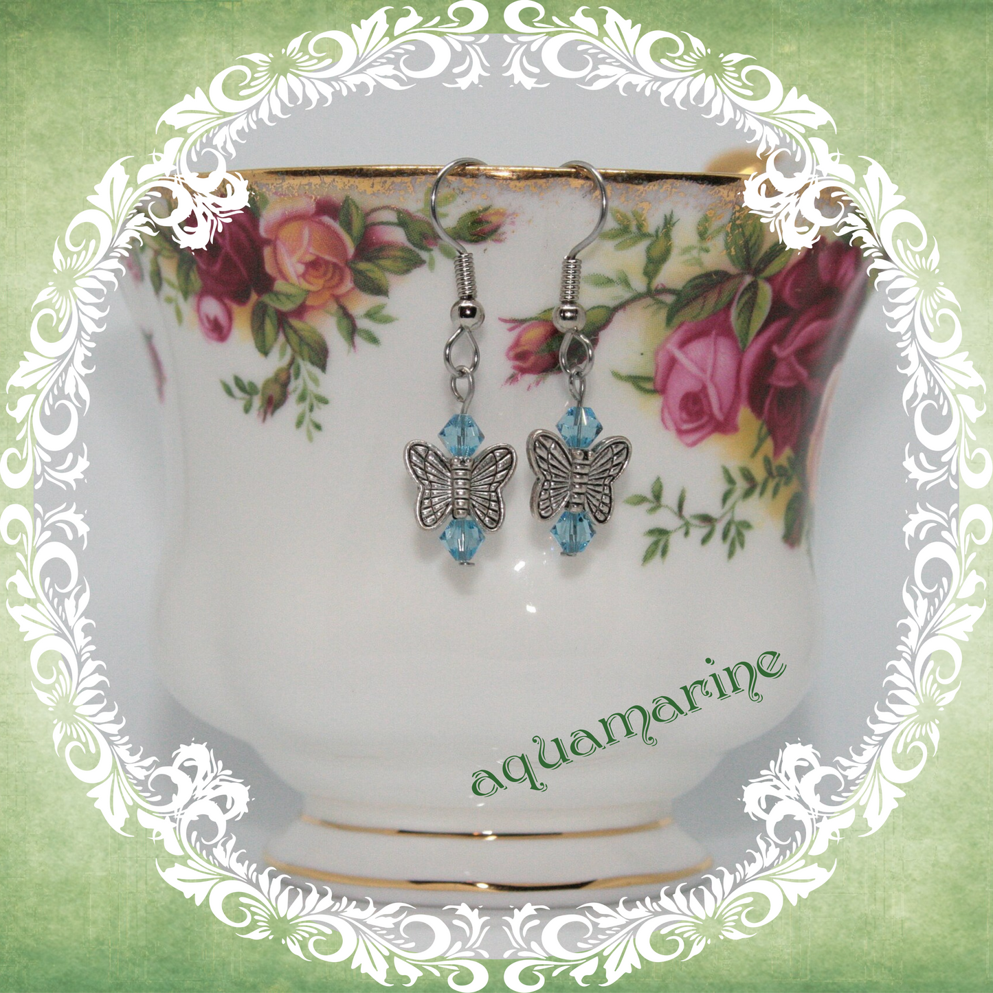 Handmade silver butterfly earrings with turquoise blue crystal beads shown on floral china teacup