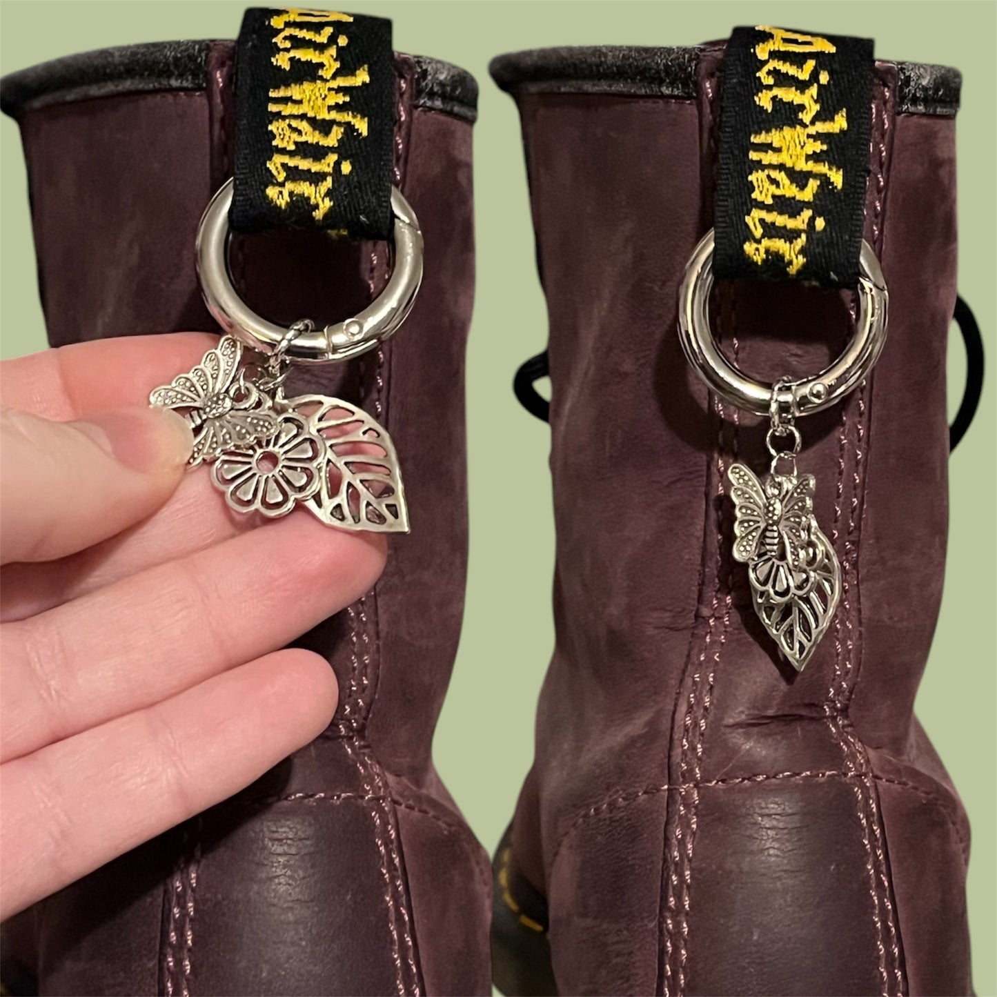 Close-up of handmade silver boot charms with butterfly, flower, and leaf designs clipped onto black boot tabs