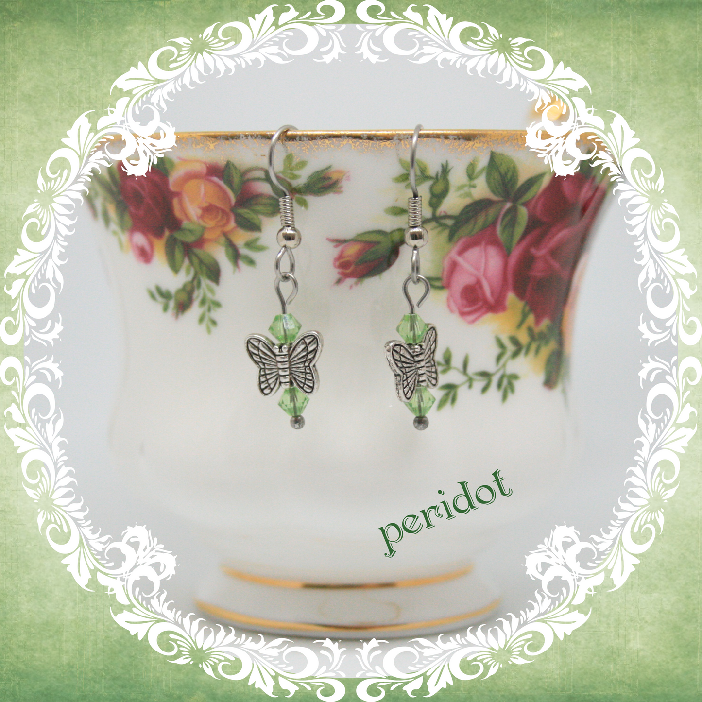 Handmade silver butterfly earrings with light green crystal beads shown on floral china teacup