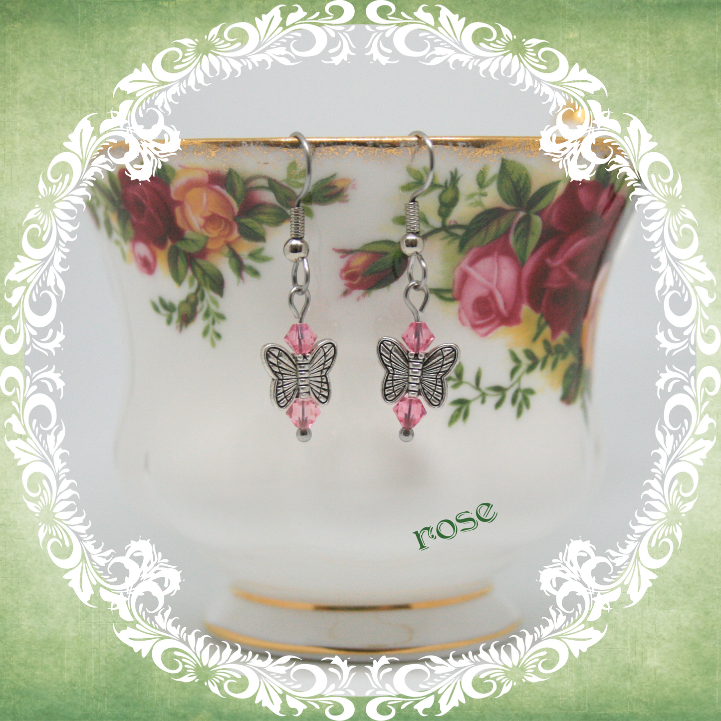 Handmade silver butterfly earrings with pink crystal beads shown on floral china teacup
