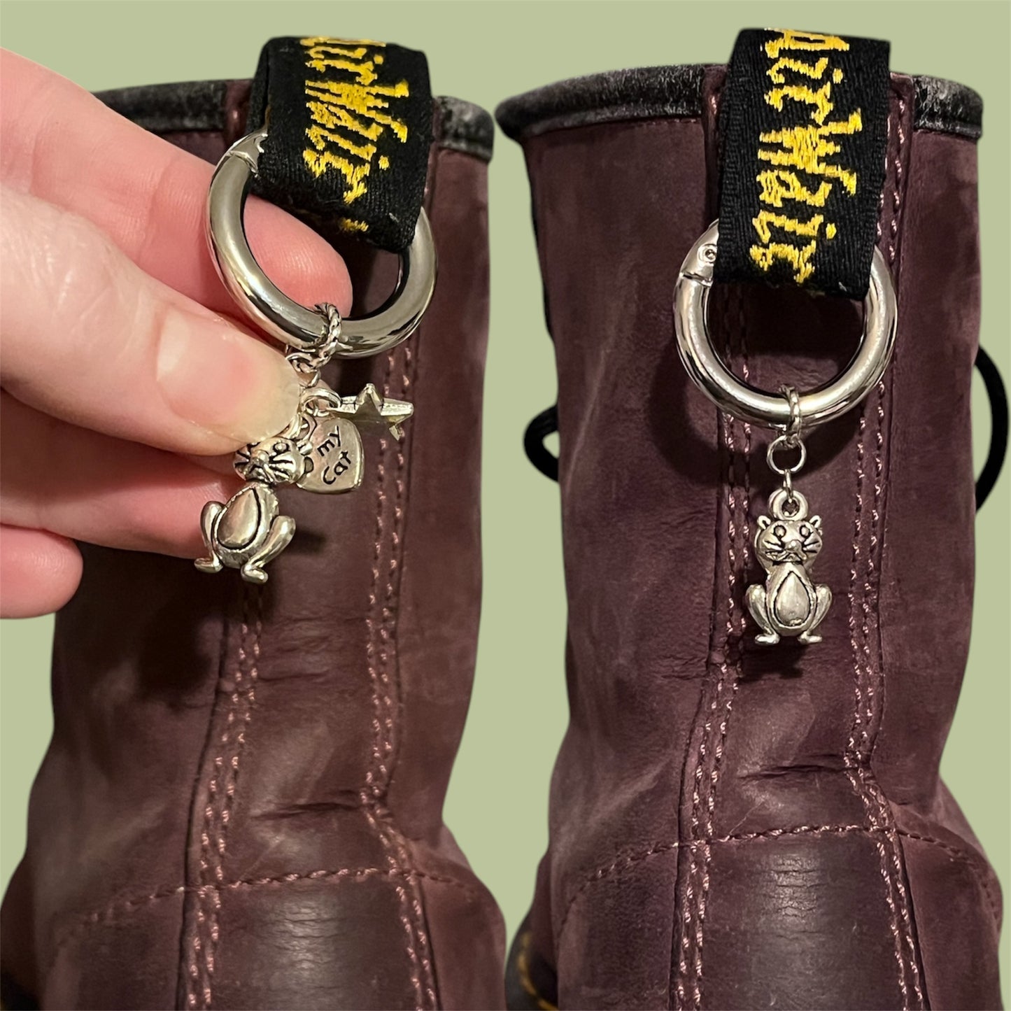 Close-up of handmade silver boot charms with sitting cat, heart reading heart my cat, and solid star designs clipped onto black boot tabs