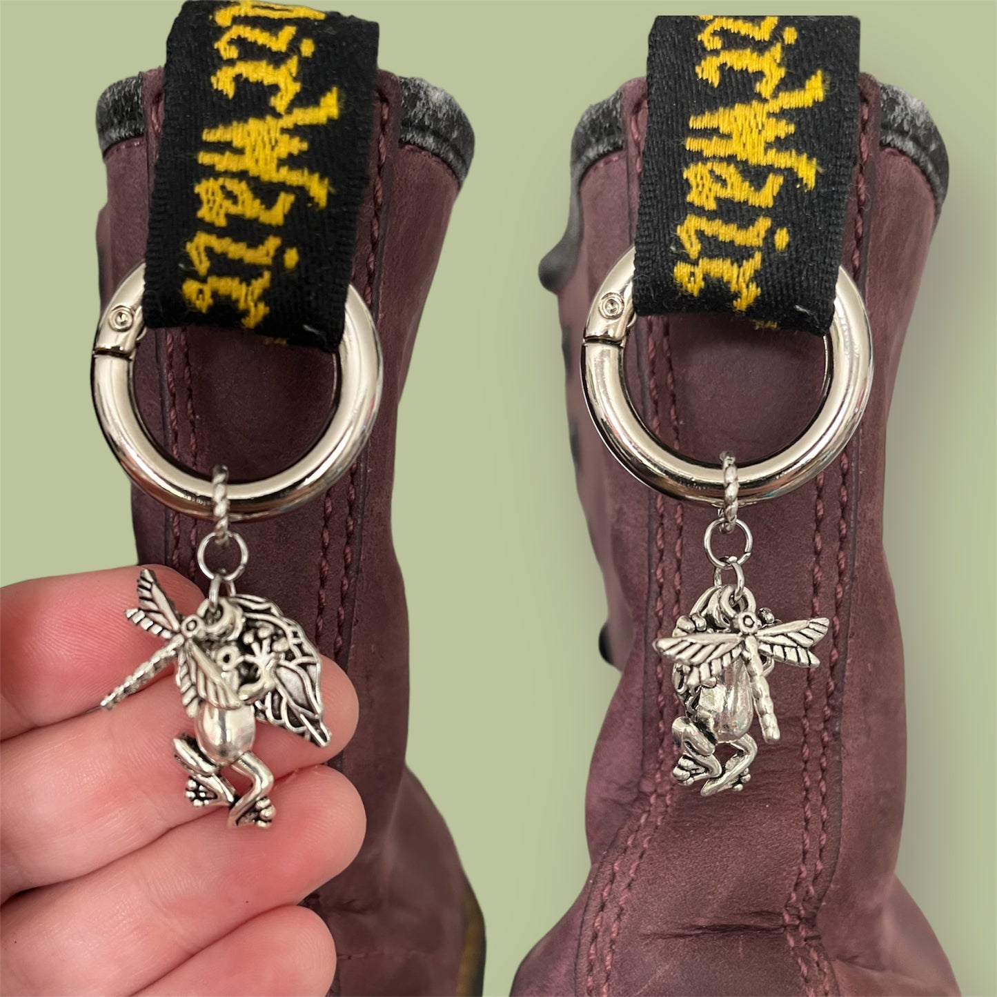 Close-up of handmade silver boot charms with dragonfly, frog, and leaf designs clipped onto black boot tabs