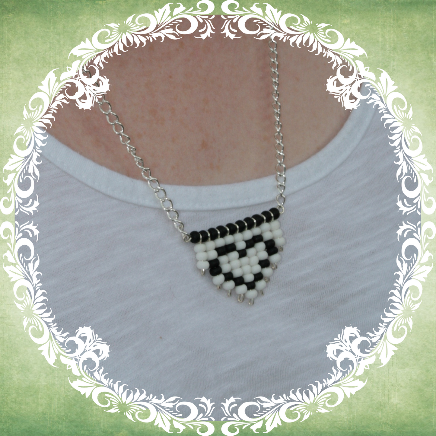 Handmade white and black heart fringe necklace with bold beadwork and playful fringe design, featuring a silver-plated chain, pictured on white t-shirt, alternate view.