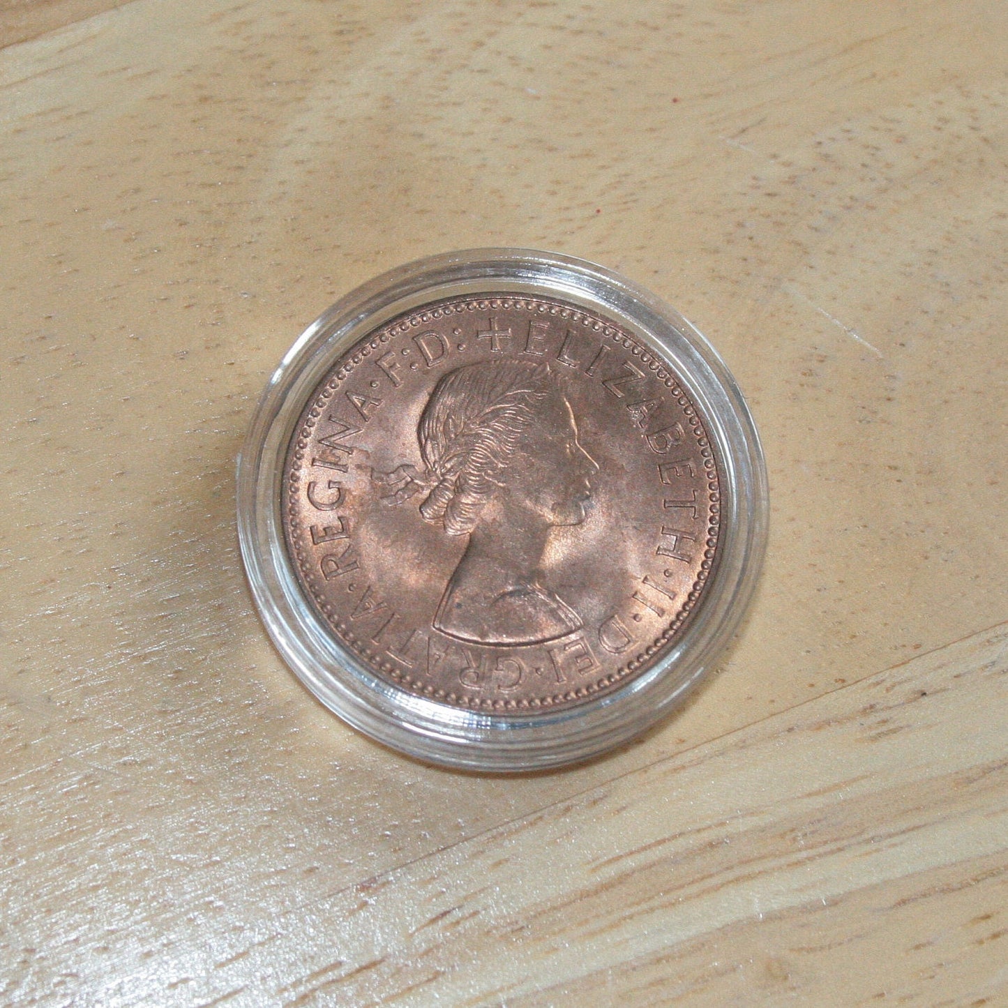 Queen Elizabeth II copper half penny coin in protective capsule, obverse