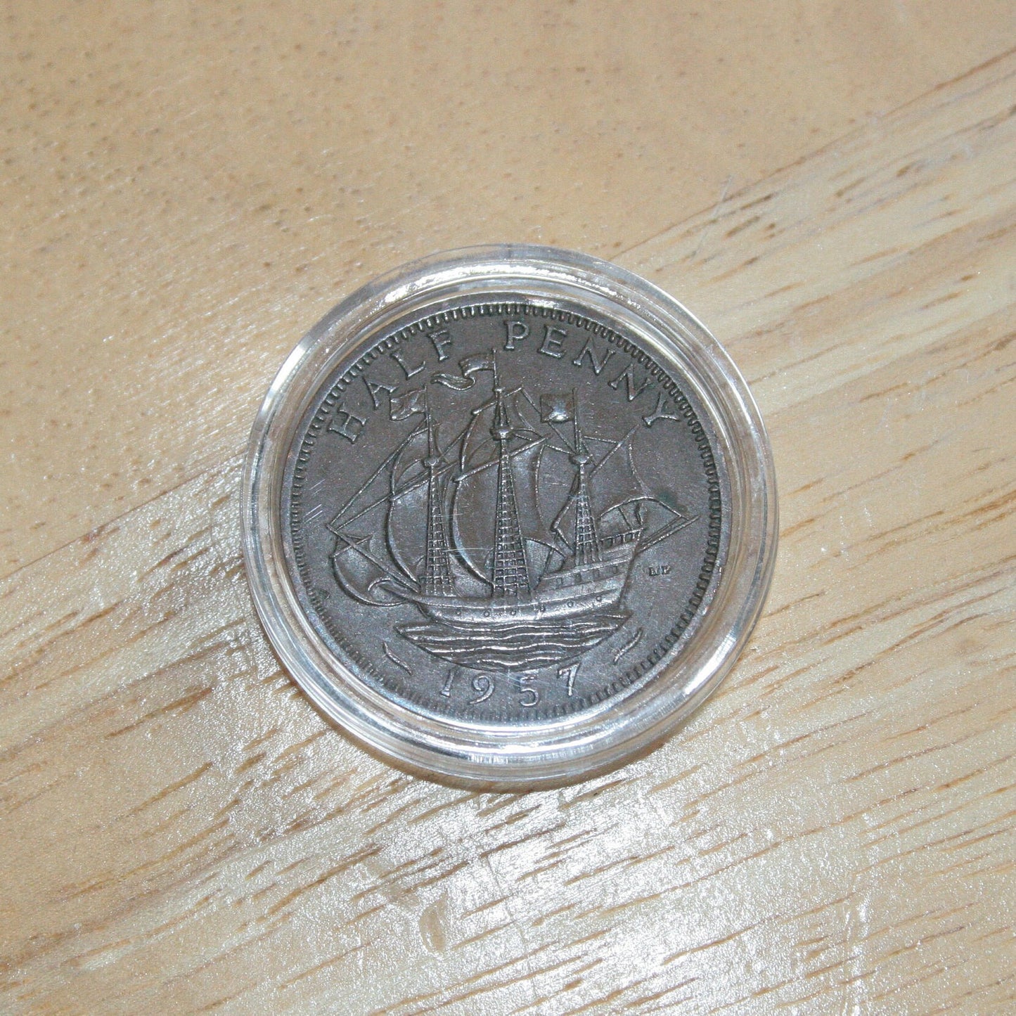 Queen Elizabeth II copper half penny coin in protective capsule, reverse dull 1957