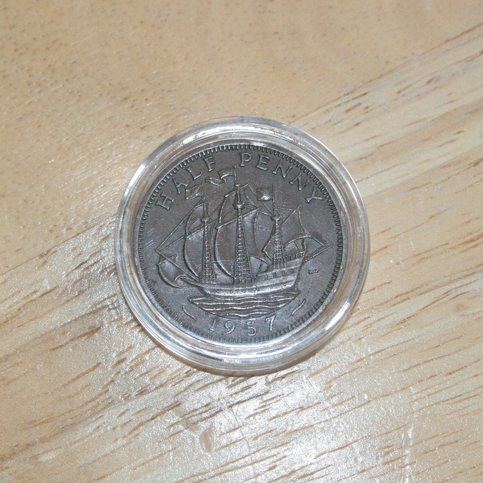 Queen Elizabeth II copper half penny coin in protective capsule, reverse dull 1957