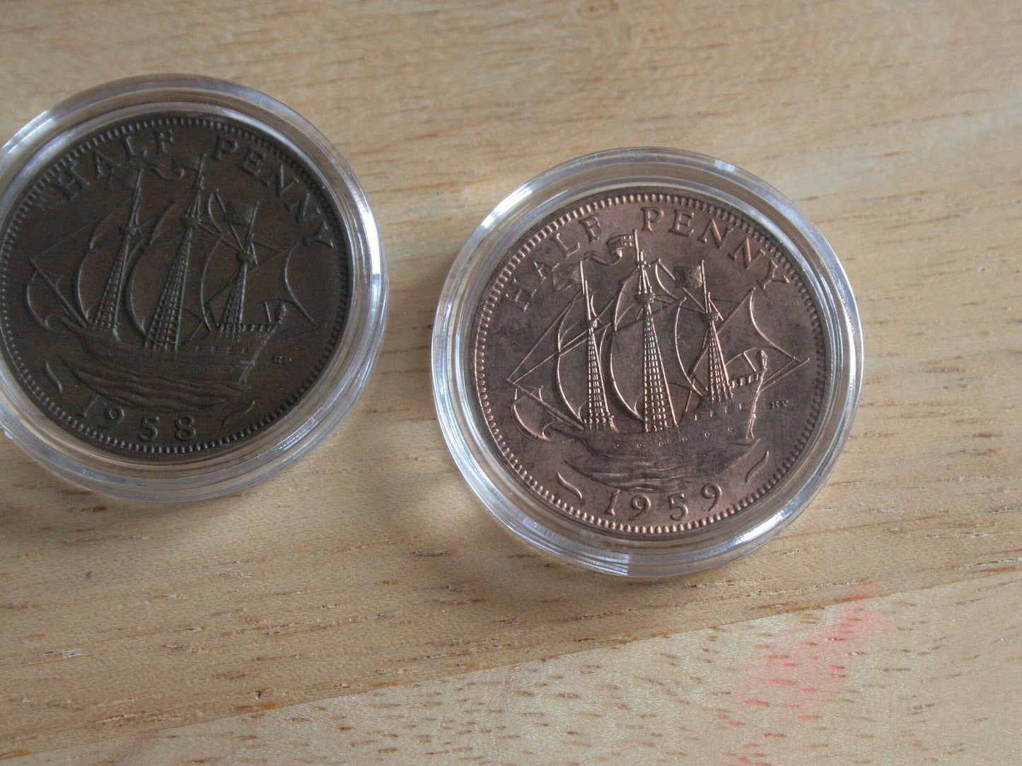 Queen Elizabeth II copper half penny coins in protective capsules, reverse 1958 and 1959