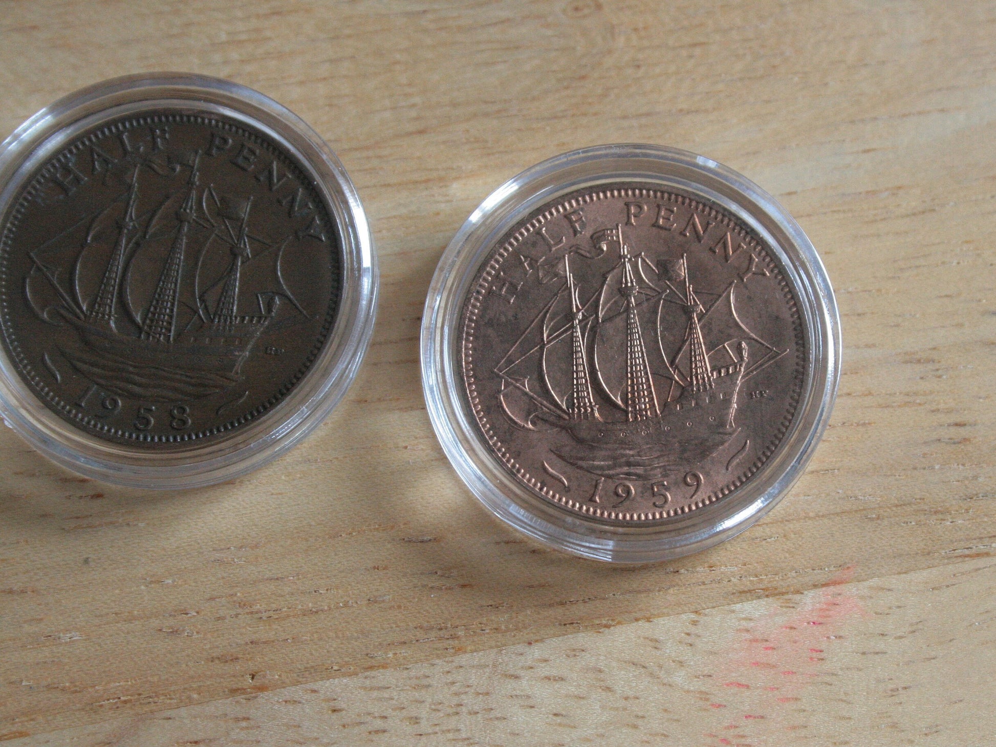 Queen Elizabeth II copper half penny coins in protective capsules, reverse 1958 and 1959