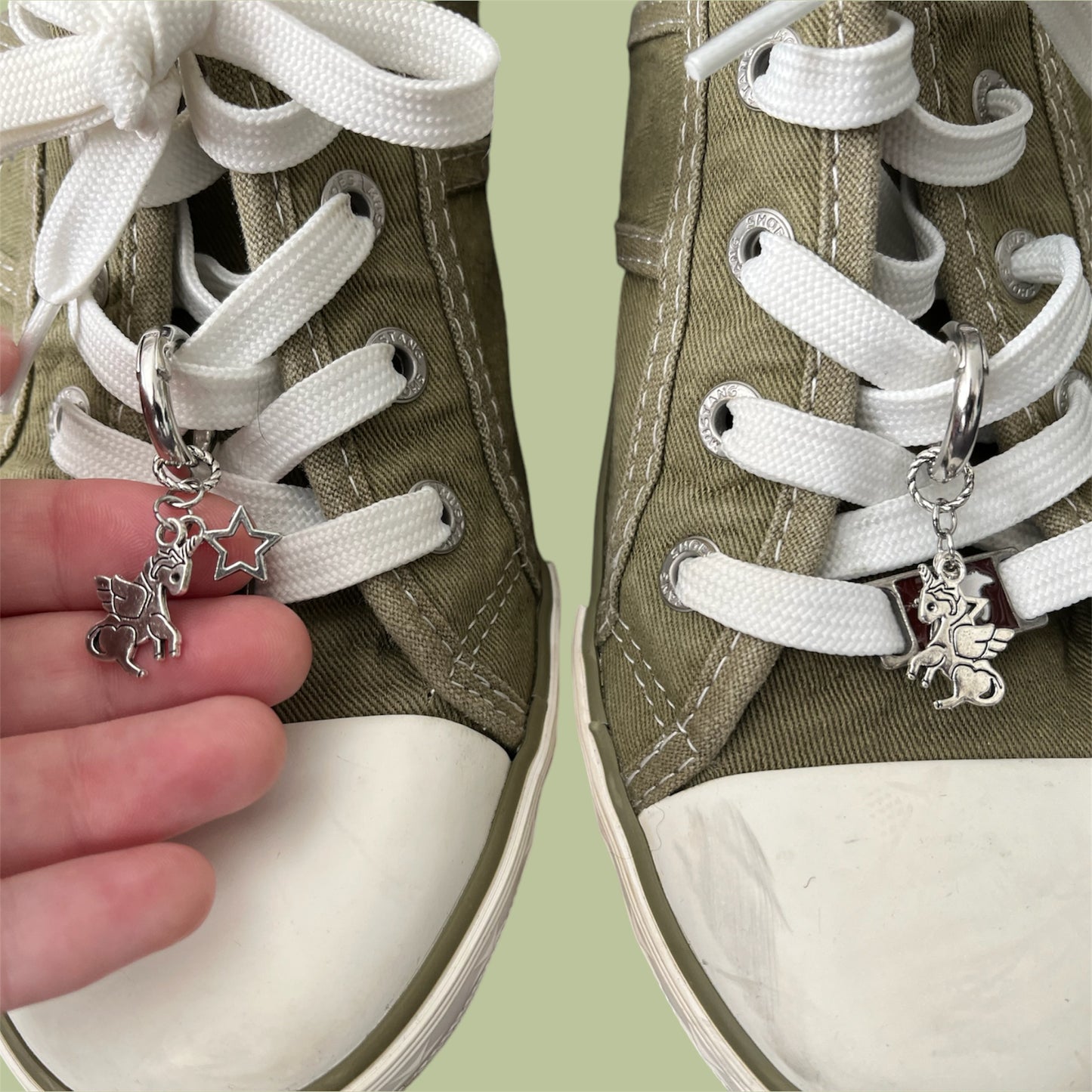 Close-up of handmade silver lace charms with unicorn and open star designs clipped onto white shoelaces