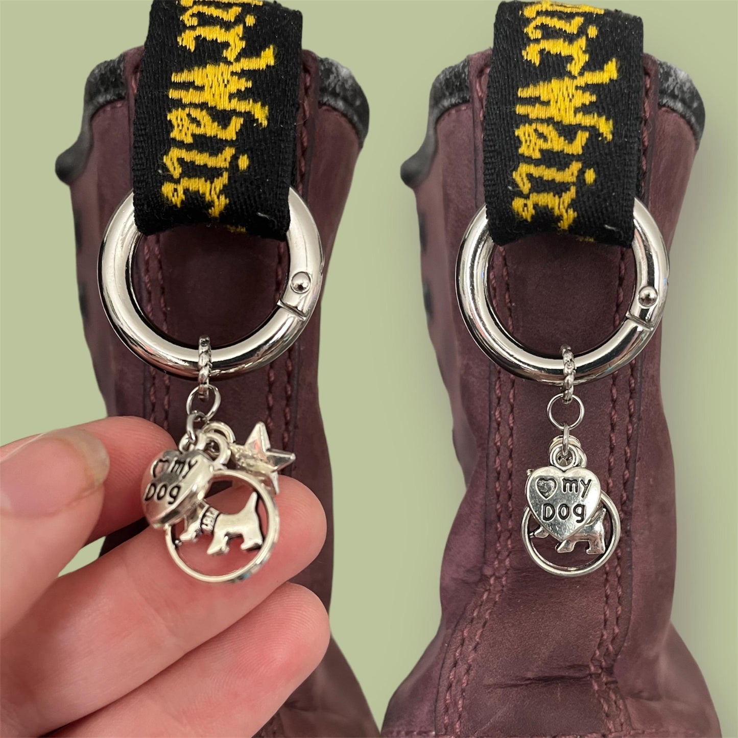 Close-up of handmade silver boot charms with heart saying heart my dog, circle with a dog in the centre, and star designs clipped onto black boot tabs
