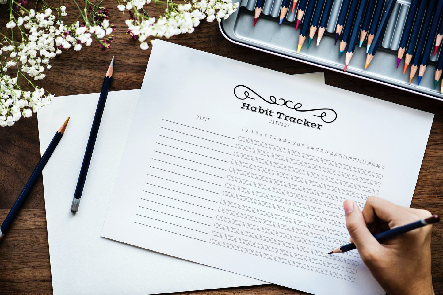 Printable habit tracker in front of person holding colouring pencil