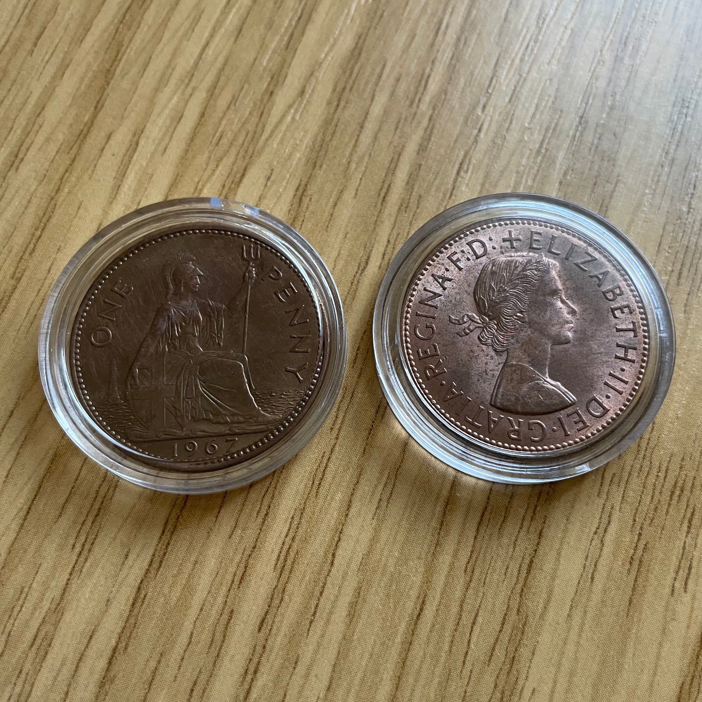Queen Elizabeth II copper one penny coins in protective capsules, obverse and reverse