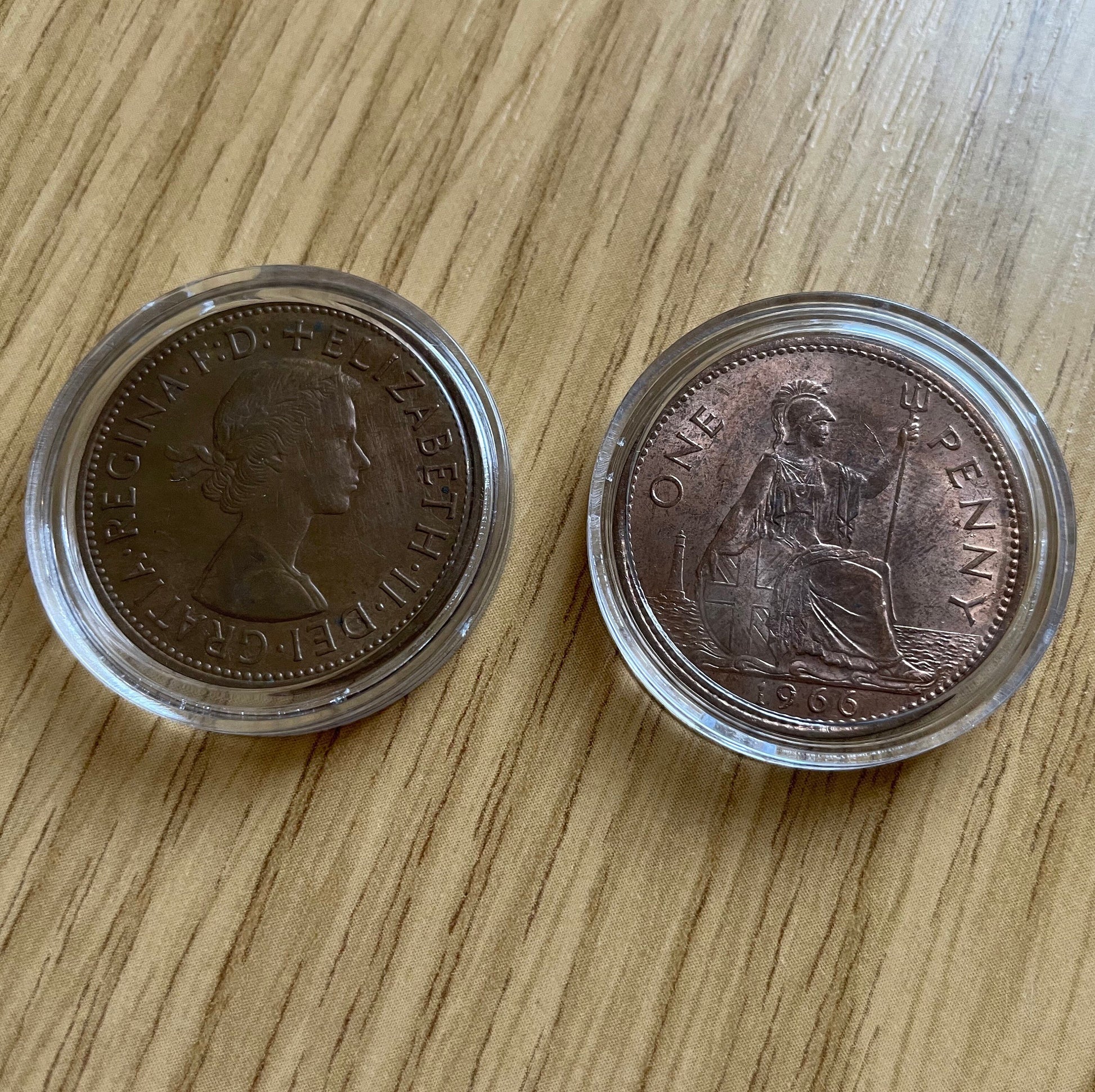 Queen Elizabeth II copper one penny coins in protective capsules, obverse and reverse