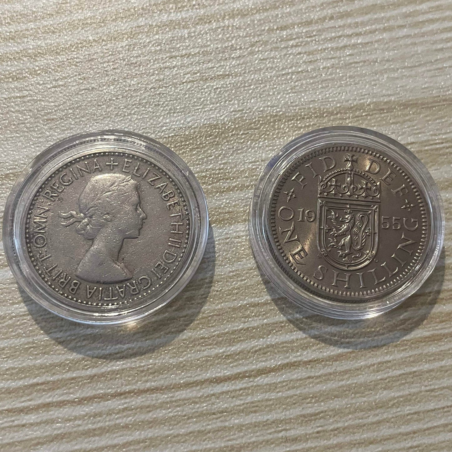 Queen Elizabeth II silver one shilling coins in protective capsules, obverse and reverse