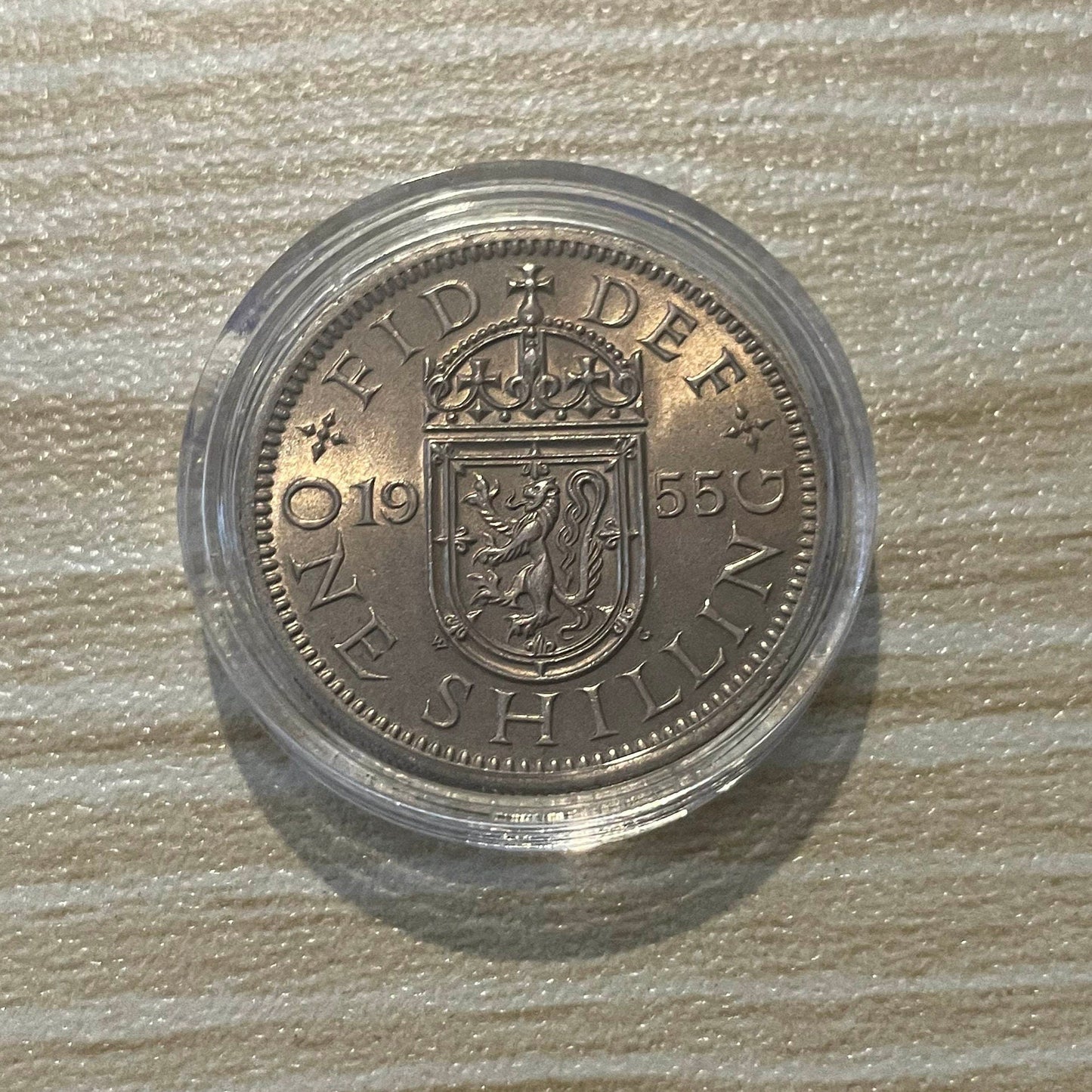 Queen Elizabeth II silver one shilling coin in protective capsule, reverse