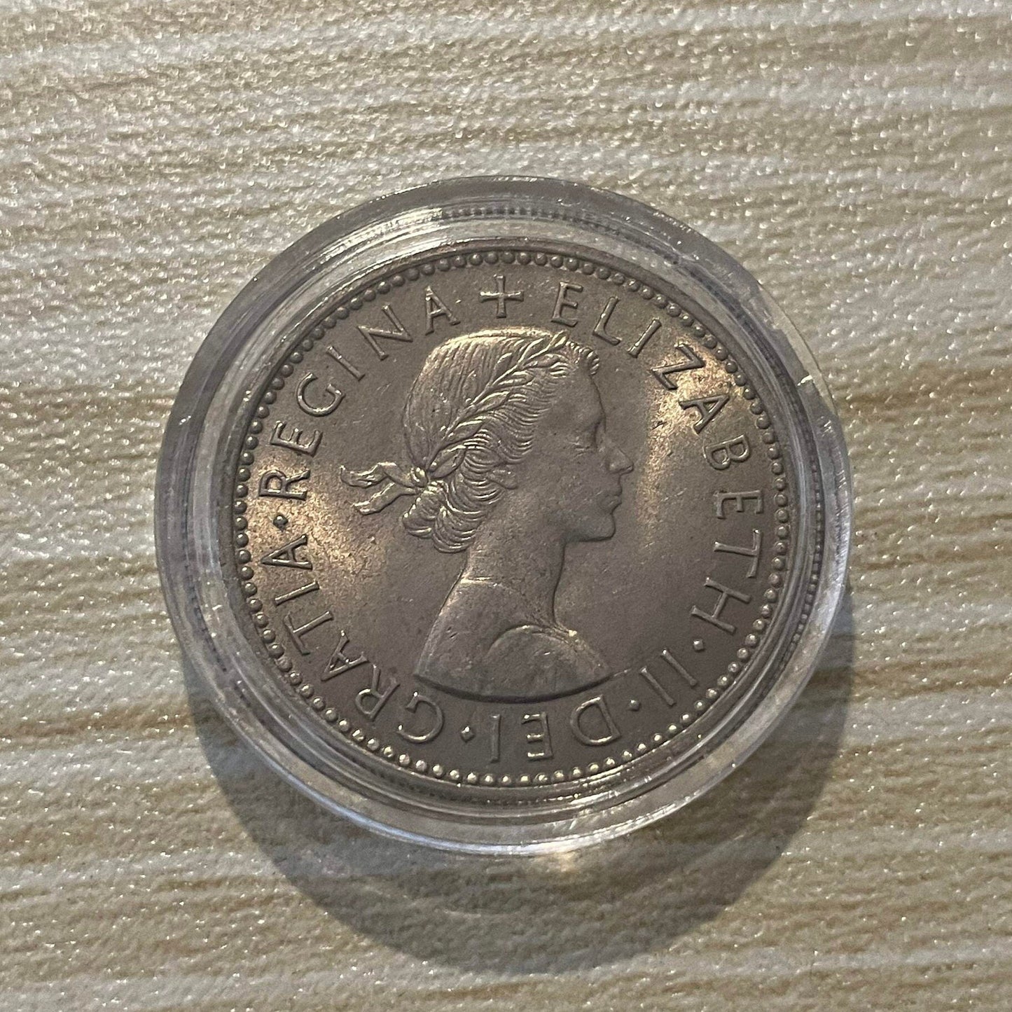 Queen Elizabeth II silver one shilling coin in protective capsule, obverse