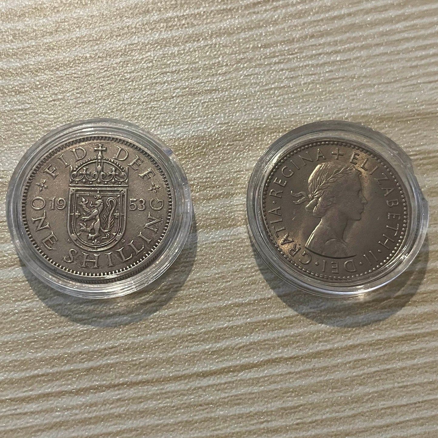 Queen Elizabeth II silver one shilling coins in protective capsules, obverse and reverse