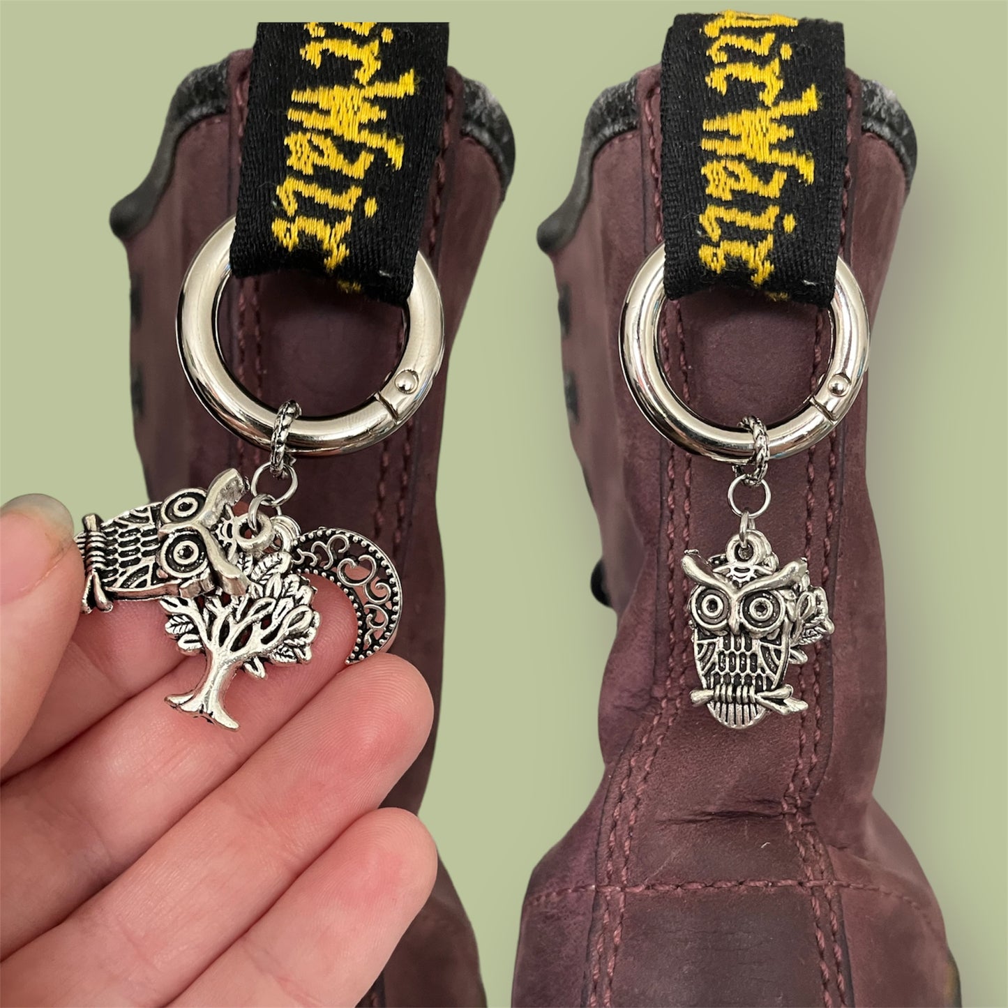 Close-up of handmade silver boot charms with owl, tree, and filigree crescent moon designs clipped onto black boot tabs
