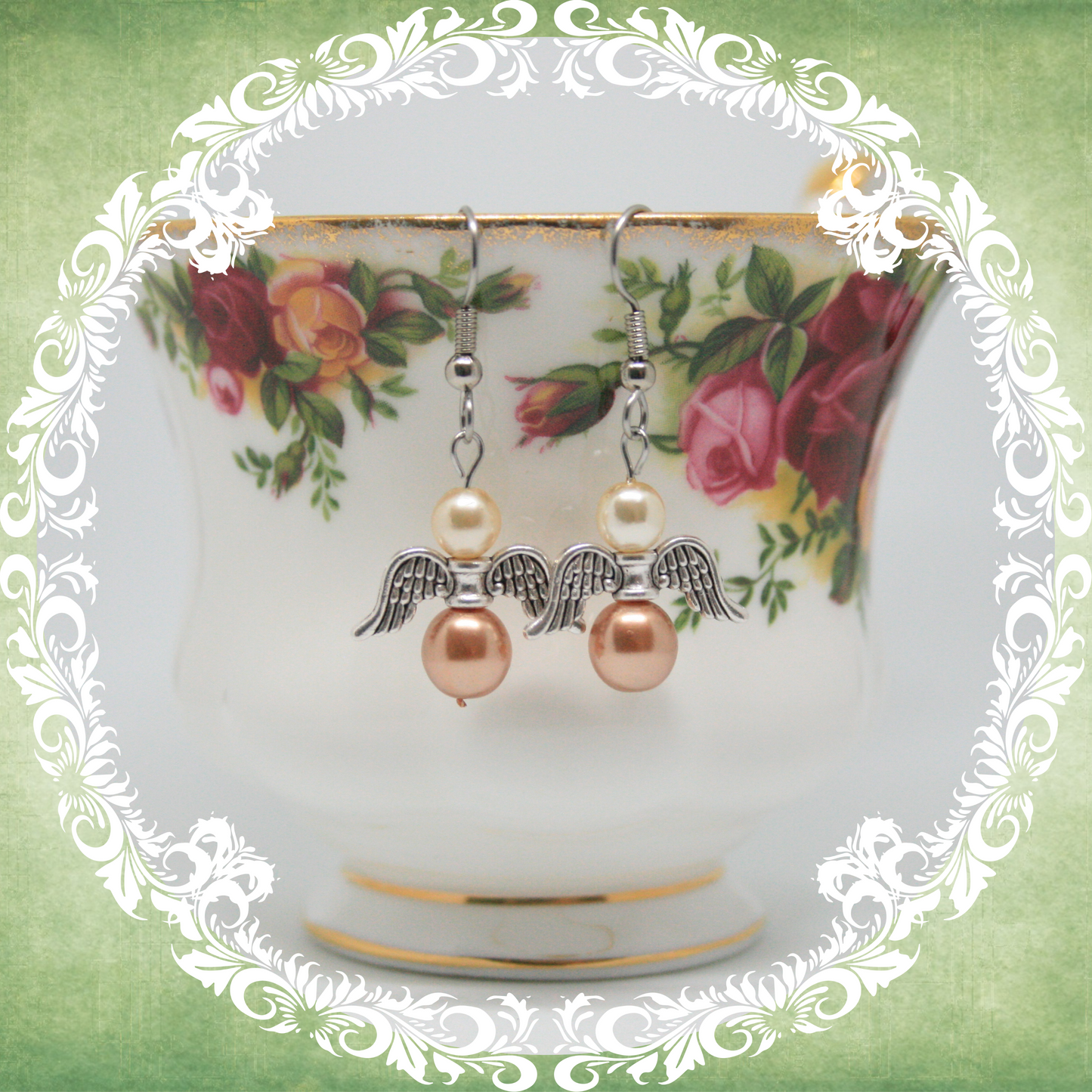 Handmade angel wing dangle earrings with cream and light brown pearls on stainless steel ear wires shown on vintage floral teacup