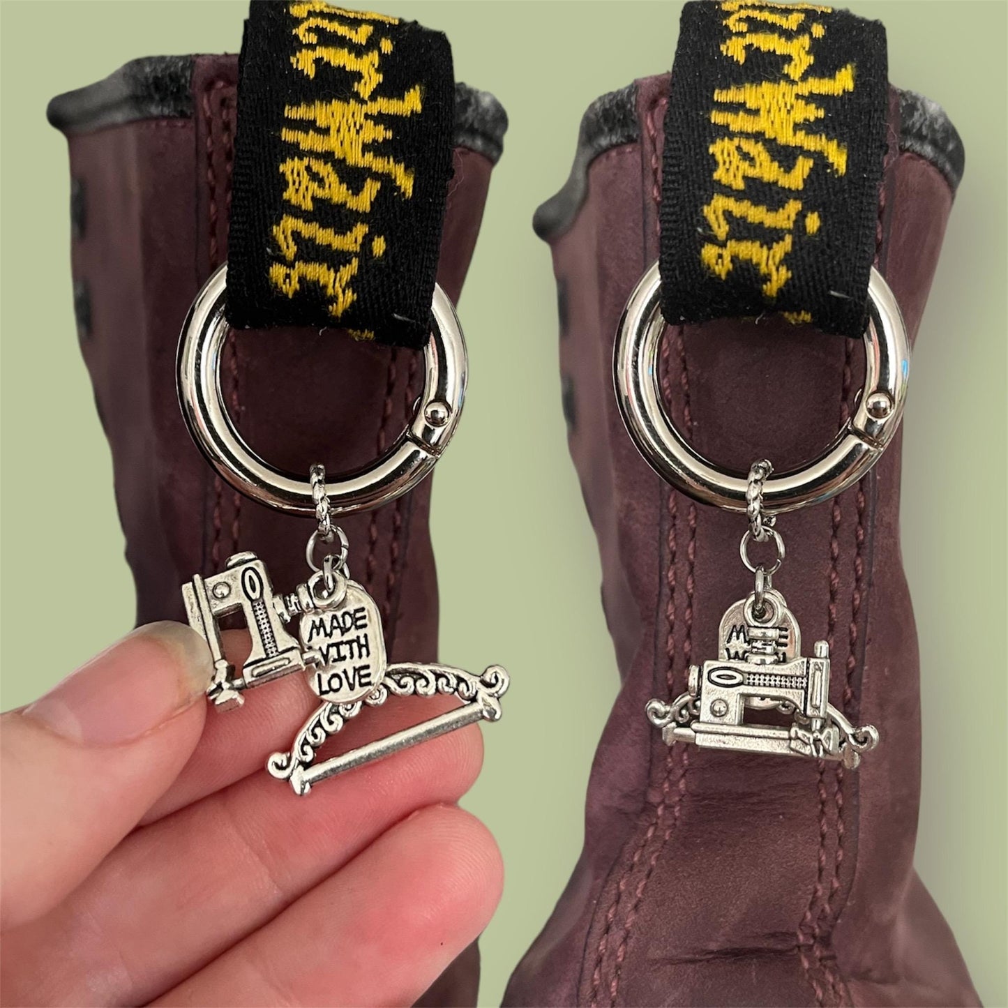 Close-up of handmade silver boot charms with sewing machine, tag saying made with love, and clothes hanger designs clipped onto black boot tabs