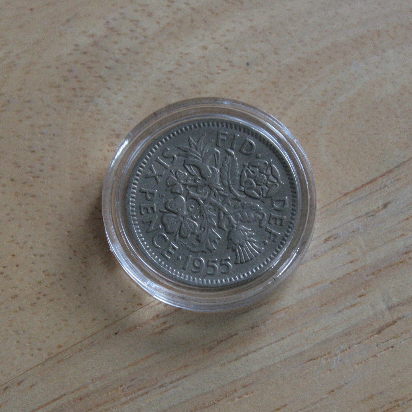 Queen Elizabeth II silver sixpence coin in protective capsule, reverse