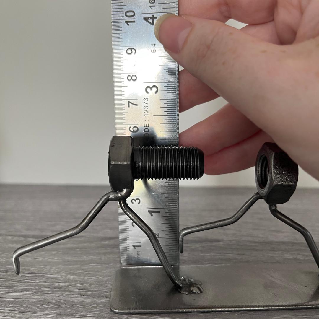 Whimsical sculpture of a bolt chasing a nut, symbolising the playful pursuit of connection. Ideal for tinkerers, engineers, and lovers of metal art and puns. Showing height measurement.