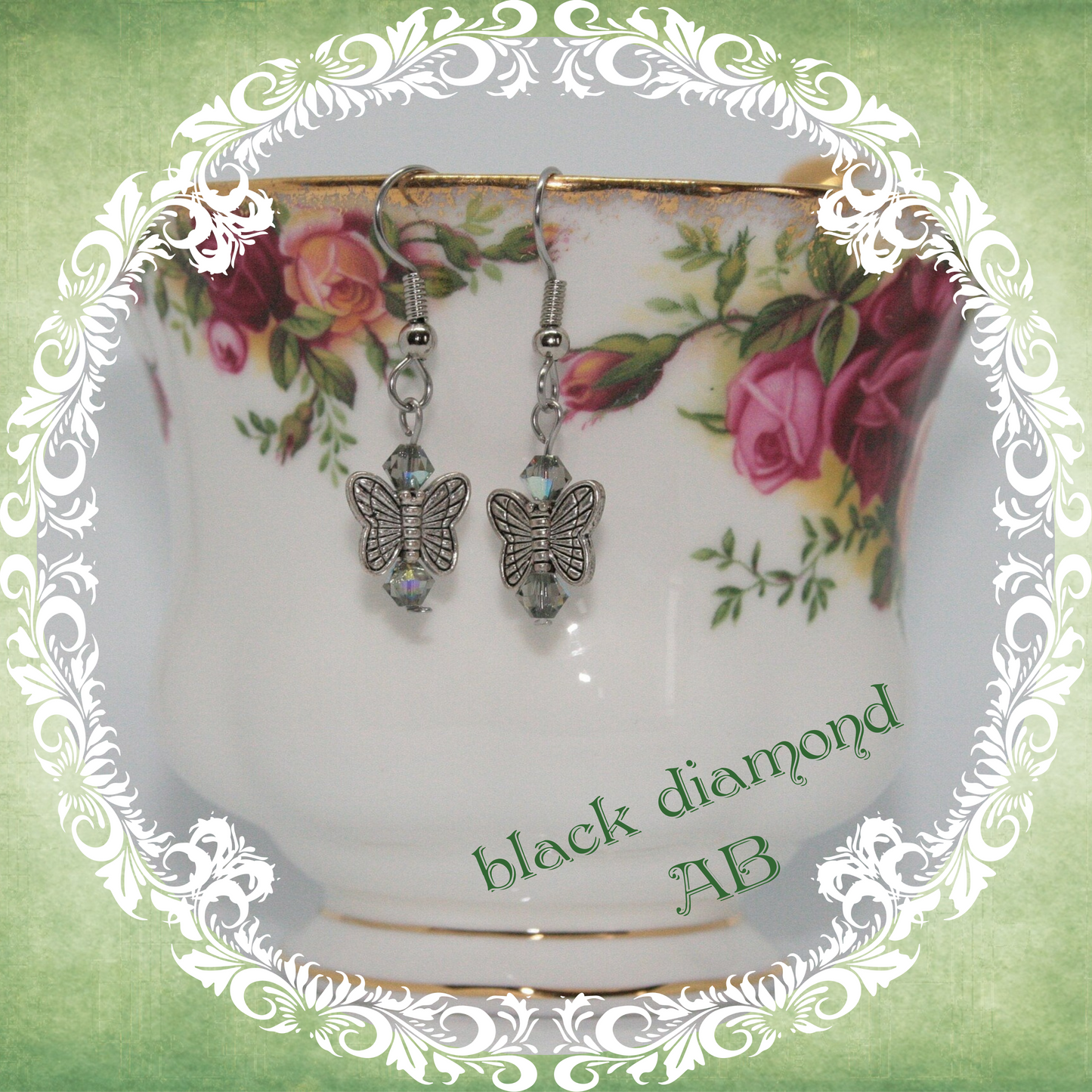 Handmade silver butterfly earrings with black sparkling crystal beads shown on floral china teacup