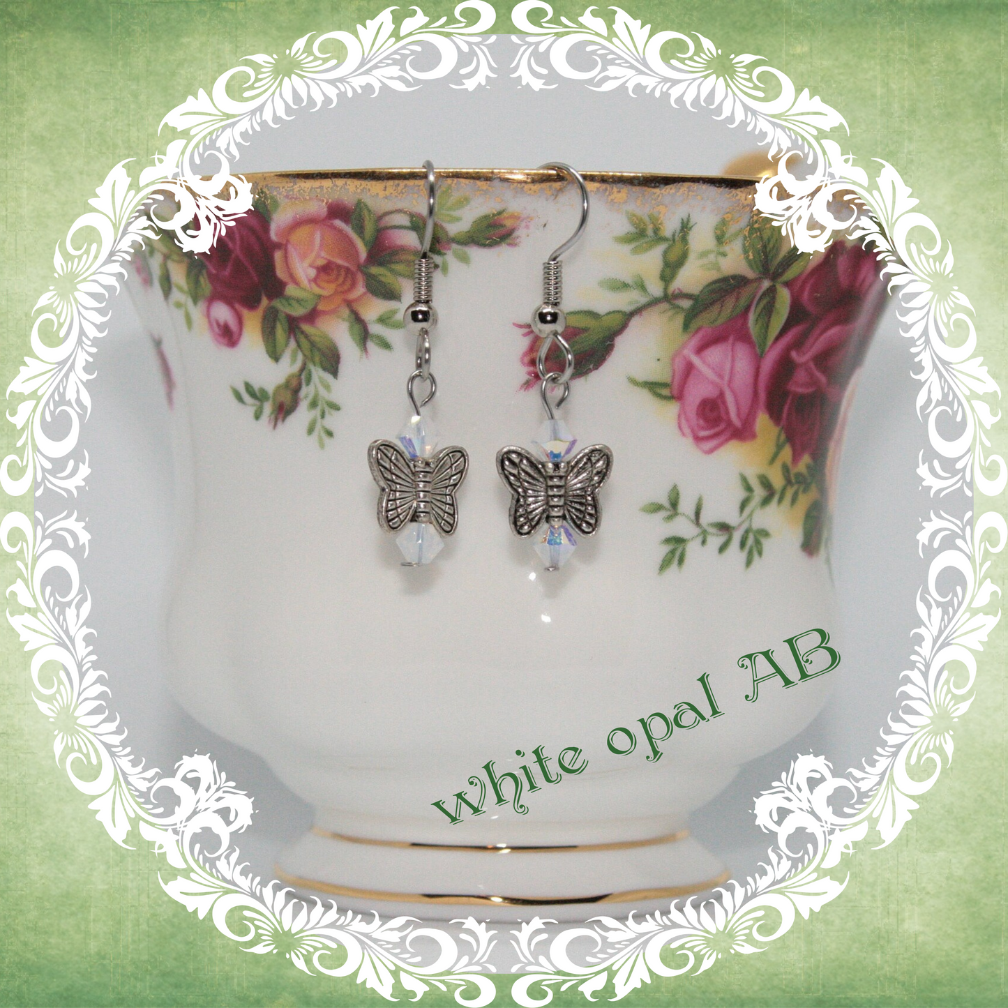 Handmade silver butterfly earrings with clear white crystal beads shown on floral china teacup