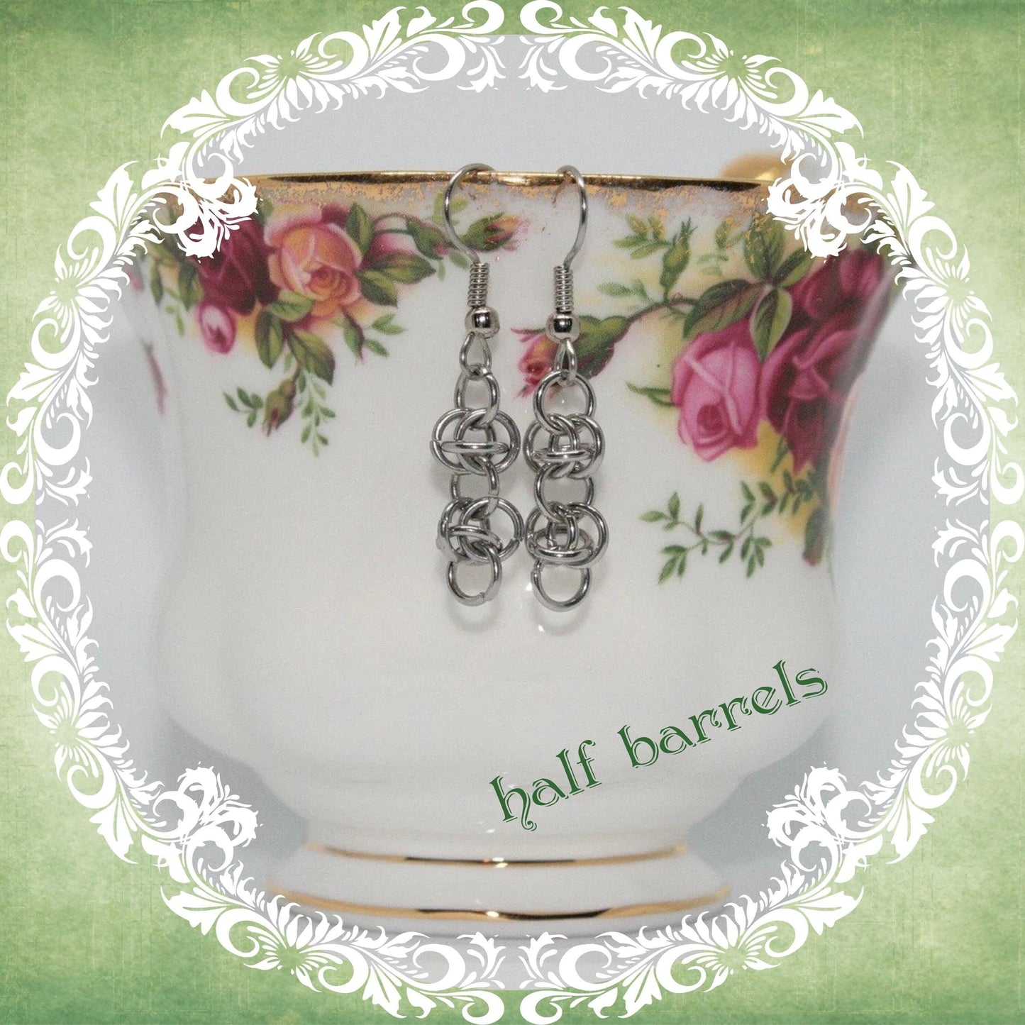 Handmade stainless steel chainmail dangle earrings shown on vintage floral teacup, modern medieval fashion accessory, half barrels design