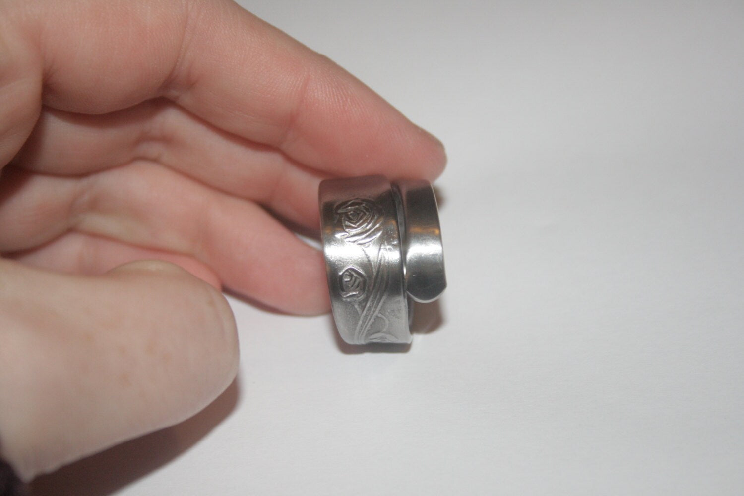 Upcycled silver ring made from antique spoon with rose design, held by a woman